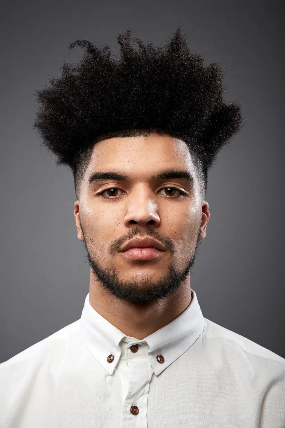 Man with high top afro with beard and white shirt