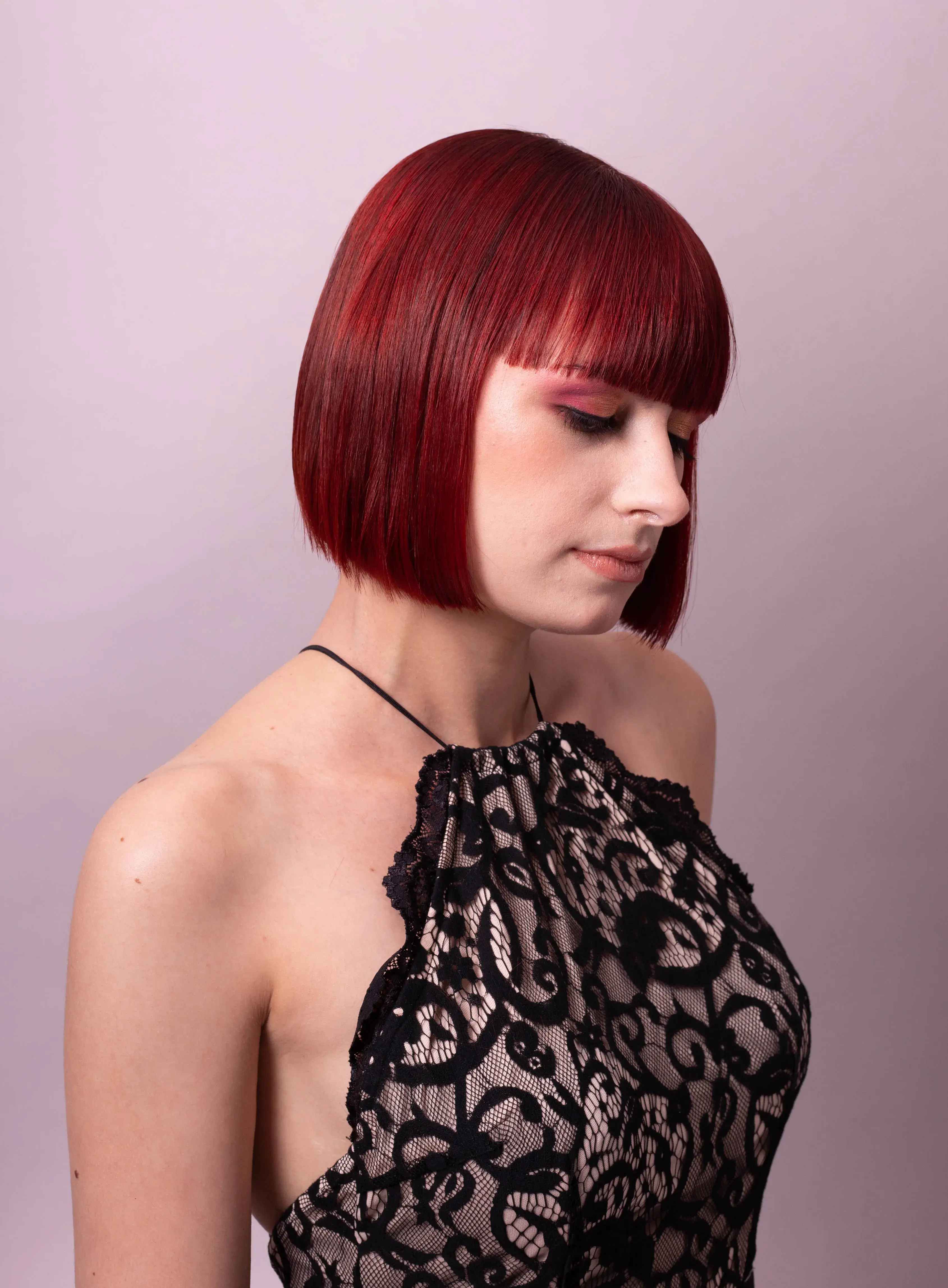 Woman with red bob cut with a full fringe looking down