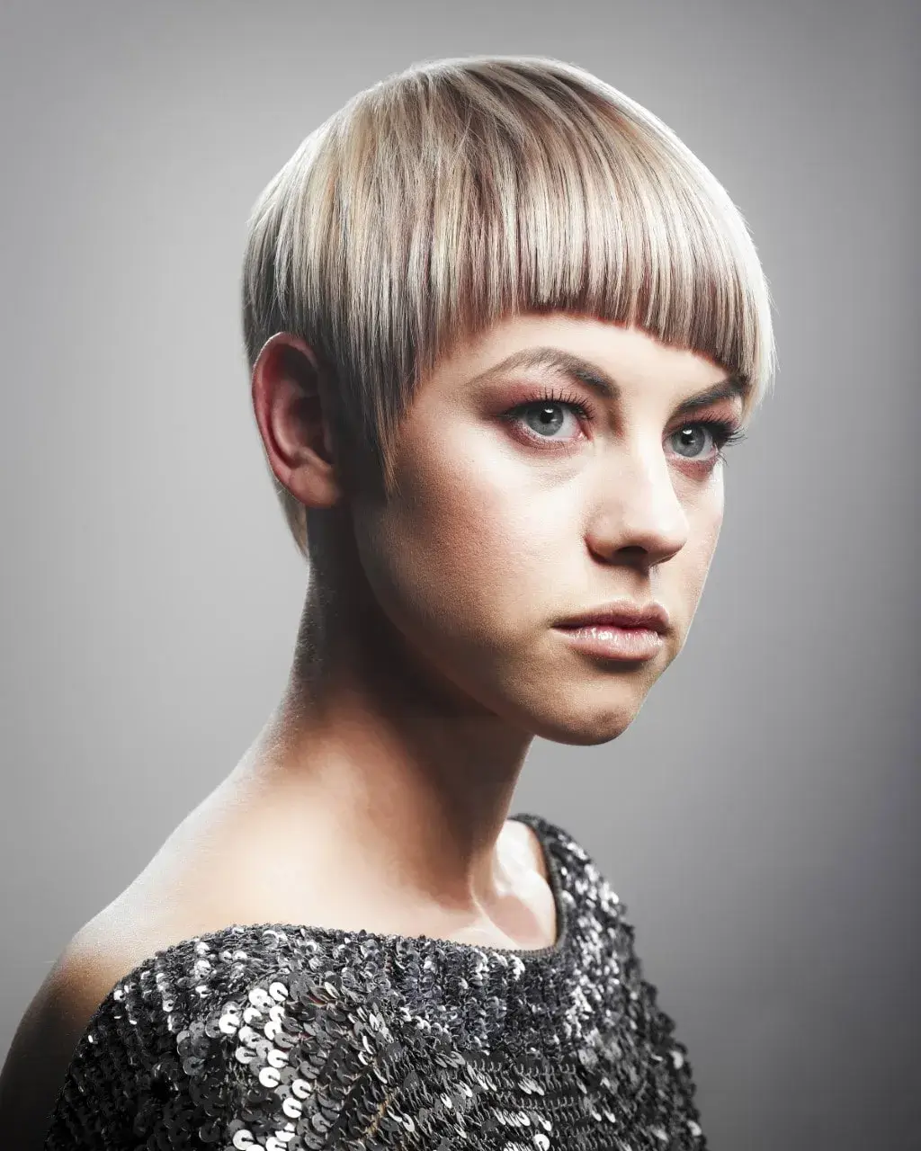 Woman with blonde highlights and pixie cut in silver sequin top